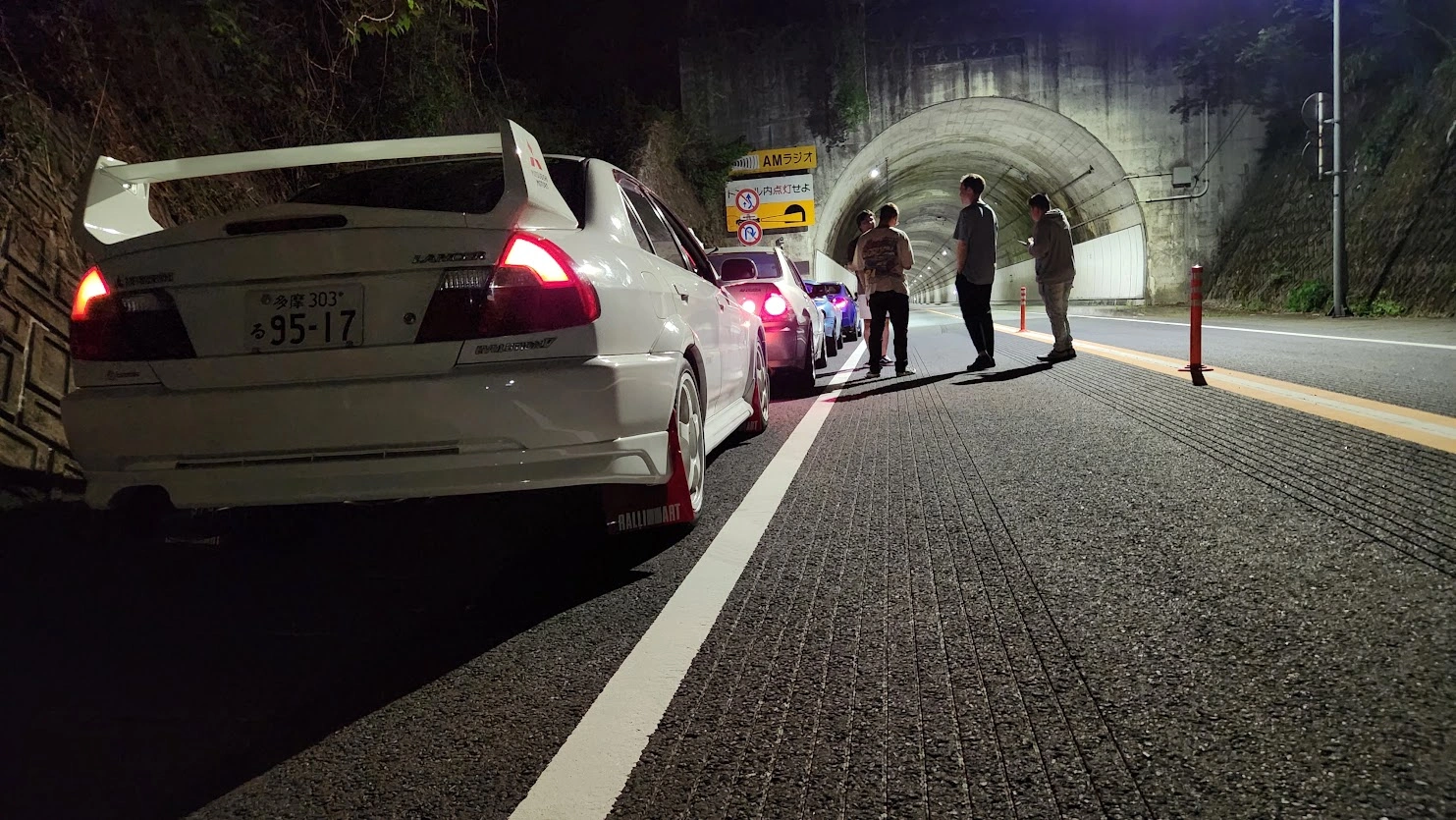 Drivers beside parked cars outside a tunnel