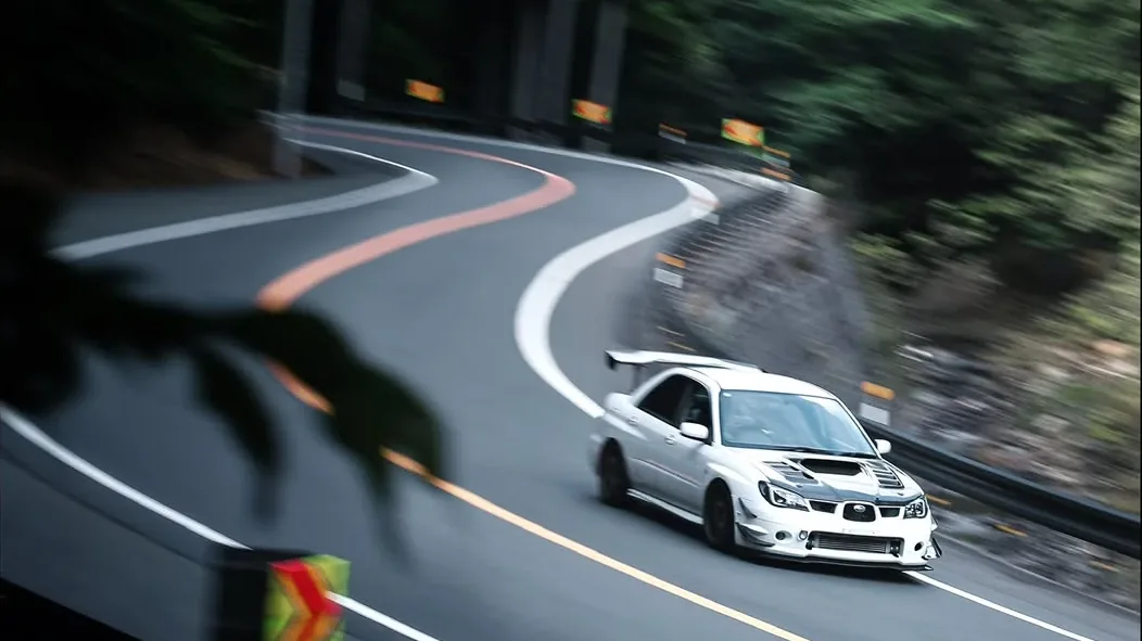 A white Subaru on a winding forest road